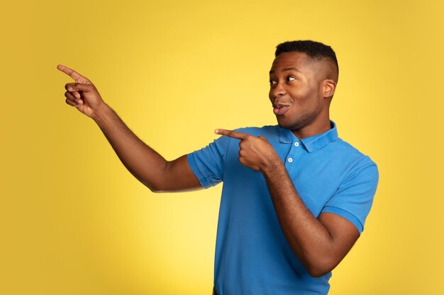 Retrato de joven afroamericano aislado en estudio amarillo, expresión facial