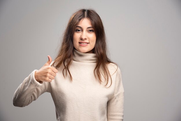 Retrato de una joven alegre mostrando un pulgar hacia arriba.