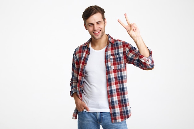 Retrato de un joven alegre que muestra gesto de paz