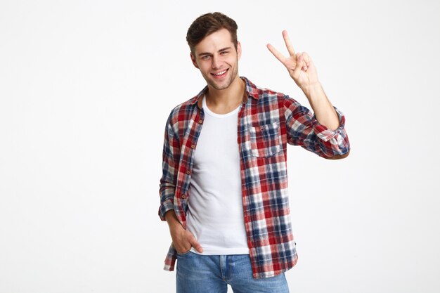 Retrato de un joven alegre que muestra gesto de paz