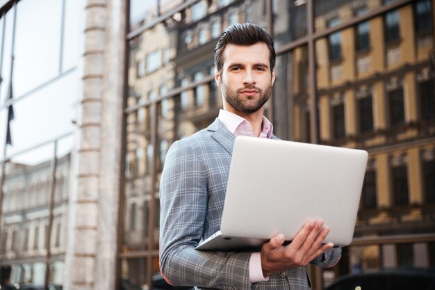 Retrato de un joven apuesto en chaqueta con laptop