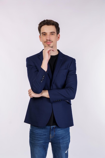 Retrato de un joven apuesto hombre de negocios que mira confiado a la cámara con una sonrisa con los brazos cruzados y la mano levantada en la barbilla sobre un fondo aislado