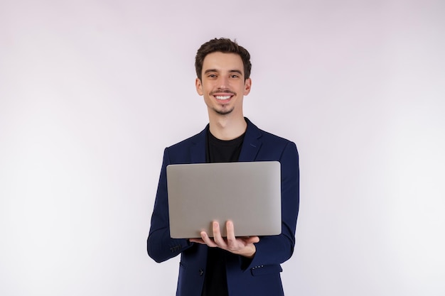 Retrato de un joven apuesto hombre de negocios sonriente sosteniendo una laptop en las manos escribiendo y navegando por páginas web aisladas de fondo blanco