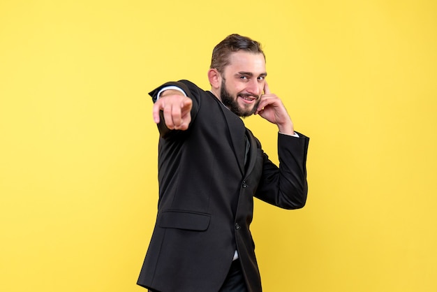 Retrato de joven apuntando y bromeando sobre amarillo