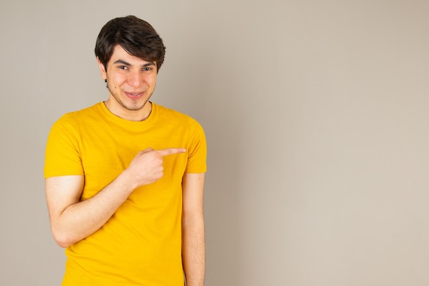Retrato de un joven apuntando con los dedos contra el gris.