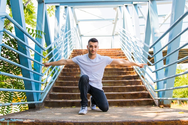 Retrato de un joven arrodillado en las escaleras estirando los brazos