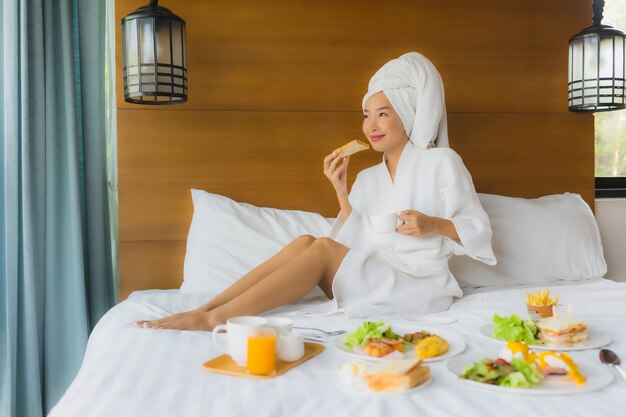 Retrato de joven asiática en cama con desayuno