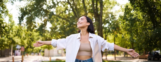 Foto gratuita retrato de una joven asiática despreocupada bailando en el parque sola disfrutando de la libertad sonriendo de alegría