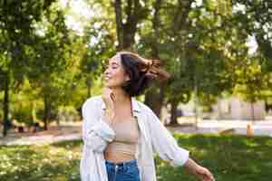 Foto gratuita retrato de una joven asiática despreocupada bailando sola en el parque disfrutando de la libertad sonriendo con alegría