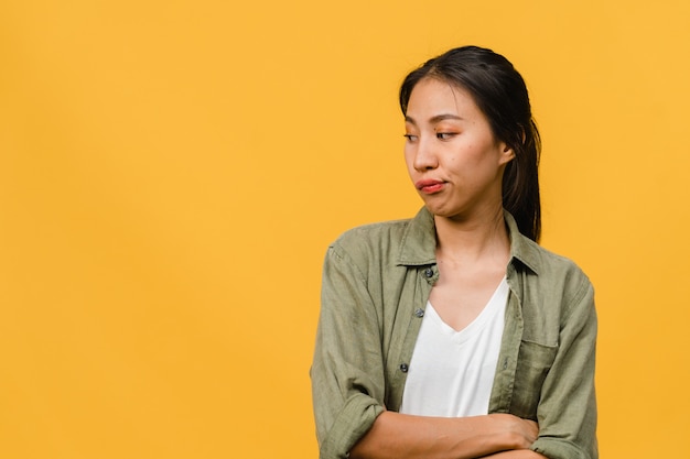 Retrato de joven asiática con expresión negativa, gritando emocionado, llorando emocionalmente enojado en ropa casual aislado en la pared amarilla con espacio de copia en blanco. Concepto de expresión facial.