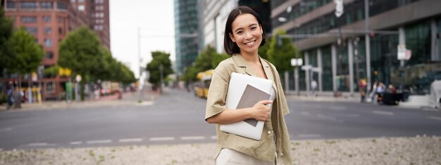 Foto gratuita retrato de una joven asiática que parece feliz y segura de ir a trabajar o a la ciudad universitaria