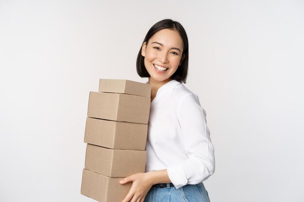 Retrato de una joven asiática sosteniendo cajas que transportan mercancías de entrega Empresaria coreana montar orden de pie voer fondo blanco