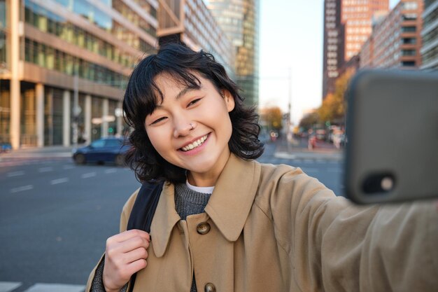 Retrato de joven asiática tomando selfie frente al edificio en el centro de la ciudad turista toma fotos