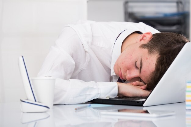 Retrato de joven asistente durmiendo en la oficina