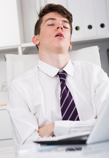 Retrato de joven asistente durmiendo en la oficina