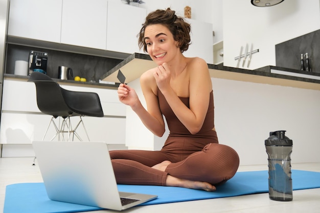 Foto gratuita retrato de una joven atleta de yoga que paga clases en línea comprando entrenamiento remoto con