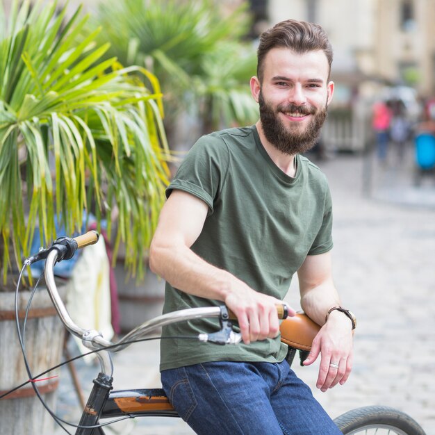 Retrato de un joven barbudo macho ciclista sentado en bicicleta