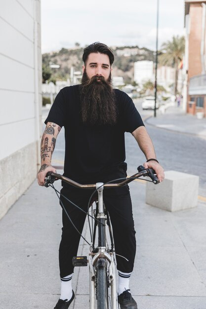 Retrato de un joven barbudo sentado en bicicleta