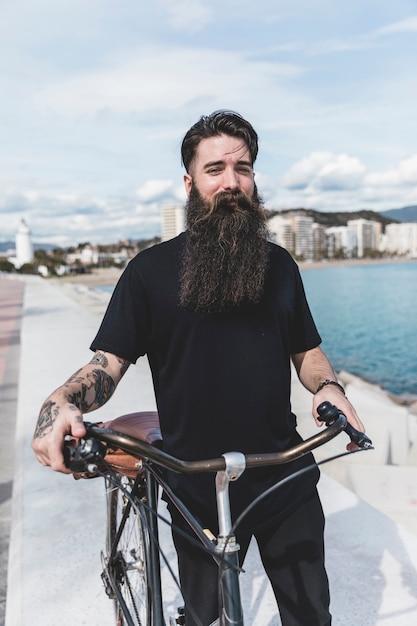 Retrato de un joven barbudo con su bicicleta