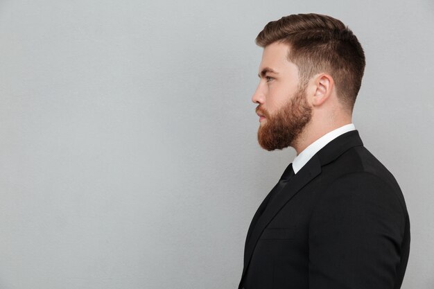 Retrato de un joven barbudo en traje mirando hacia adelante