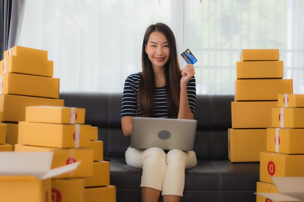 Retrato de joven bella mujer asiática con cajas de cartón y tarjeta de crédito