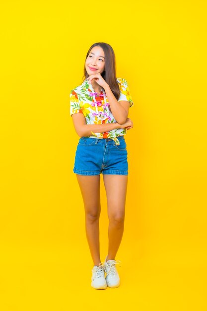 Retrato de joven y bella mujer asiática con camisa colorida en pared amarilla