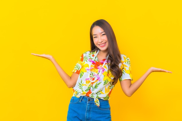 Retrato de joven y bella mujer asiática con camisa colorida en pared amarilla