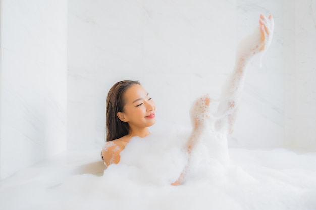 Retrato de joven y bella mujer asiática se relaja en la bañera