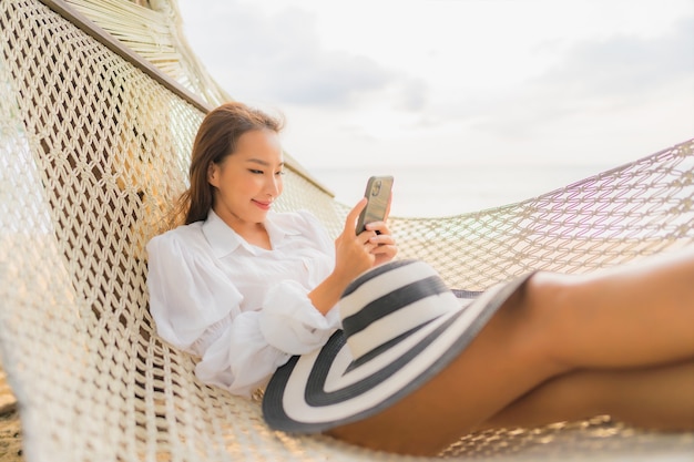 Retrato de joven y bella mujer asiática relajándose en una hamaca alrededor de la playa en vacaciones