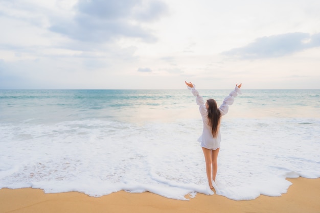 Retrato de joven y bella mujer asiática relajándose en la playa al aire libre en viajes de vacaciones