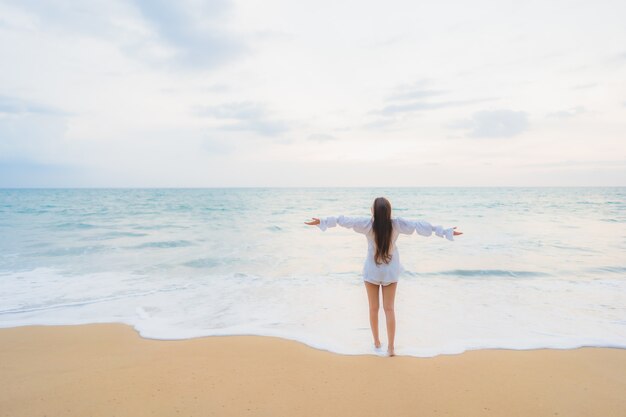 Retrato de joven y bella mujer asiática relajándose en la playa al aire libre en viajes de vacaciones