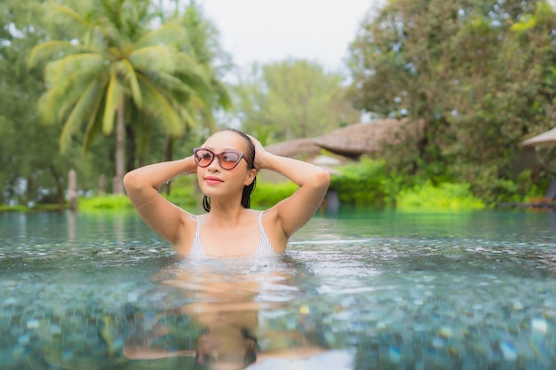 Retrato de joven y bella mujer asiática relajante alrededor de la piscina al aire libre en el hotel resort cerca del mar