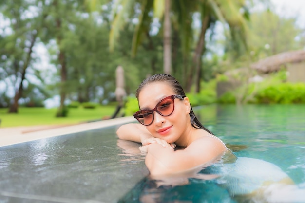 Retrato de joven y bella mujer asiática relajante alrededor de la piscina al aire libre en el hotel resort cerca del mar