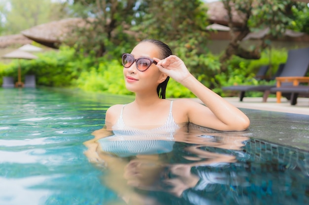 Retrato de joven y bella mujer asiática relajante alrededor de la piscina al aire libre en el hotel resort cerca del mar