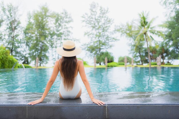 Retrato de joven y bella mujer asiática relajante alrededor de la piscina al aire libre en el hotel resort cerca del mar