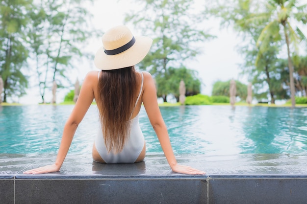 Foto gratuita retrato de joven y bella mujer asiática relajante alrededor de la piscina al aire libre en el hotel resort cerca del mar