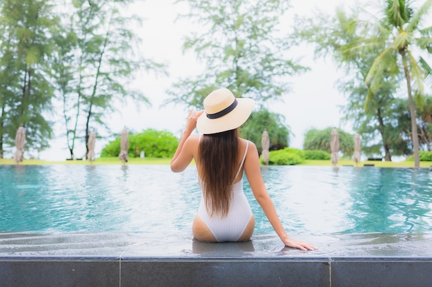 Retrato de joven y bella mujer asiática relajante alrededor de la piscina al aire libre en el hotel resort cerca del mar