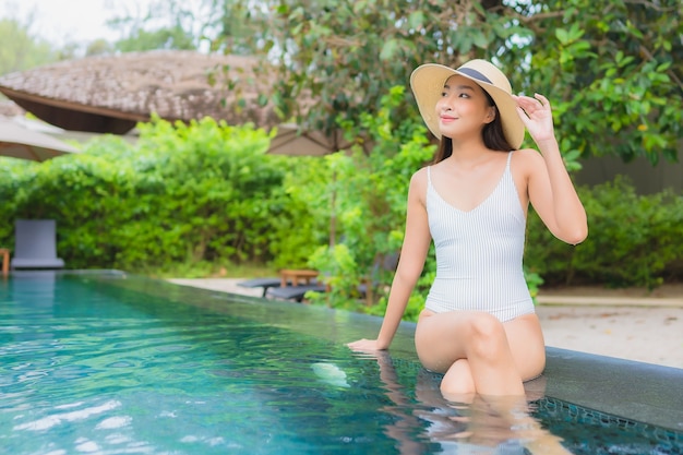 Retrato de joven y bella mujer asiática relajante alrededor de la piscina al aire libre en el hotel resort cerca del mar