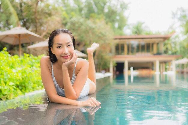 Retrato de joven y bella mujer asiática relajante alrededor de la piscina al aire libre en el hotel resort cerca del mar