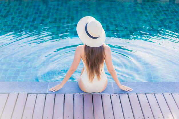 Retrato de joven y bella mujer asiática relajante alrededor de la piscina al aire libre en el hotel resort