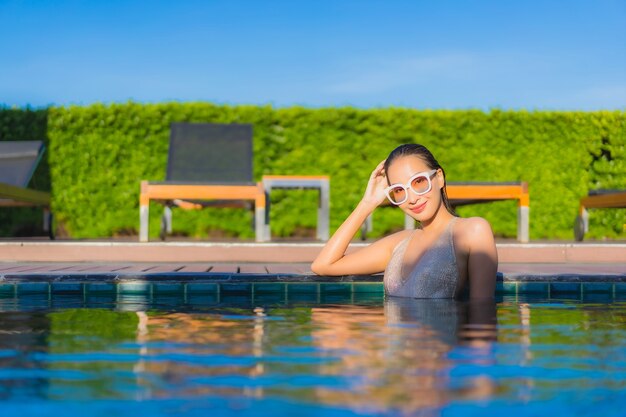 Retrato de joven y bella mujer asiática relajante alrededor de la piscina al aire libre en el hotel resort