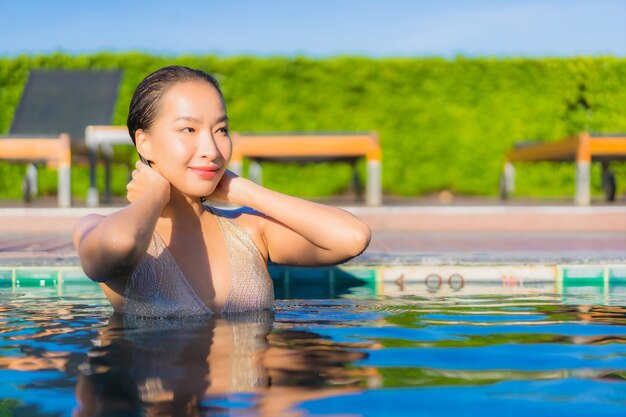 Retrato de joven y bella mujer asiática relajante alrededor de la piscina al aire libre en el hotel resort