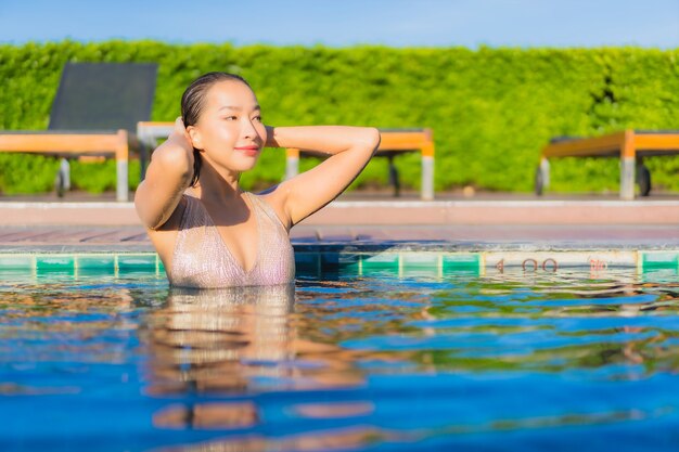 Retrato de joven y bella mujer asiática relajante alrededor de la piscina al aire libre en el hotel resort