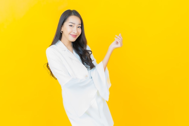 Retrato de joven y bella mujer asiática sonríe en la pared amarilla