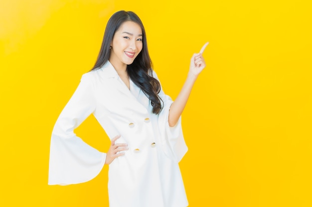 Retrato de joven y bella mujer asiática sonríe en la pared amarilla