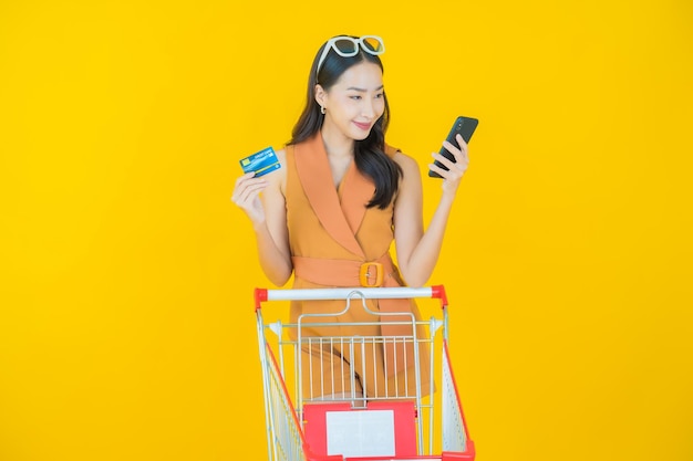 Retrato de joven y bella mujer asiática sonrisa con canasta de supermercado