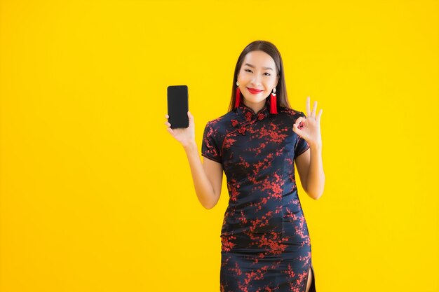 Retrato de joven y bella mujer asiática usa un vestido chino y usa un teléfono inteligente