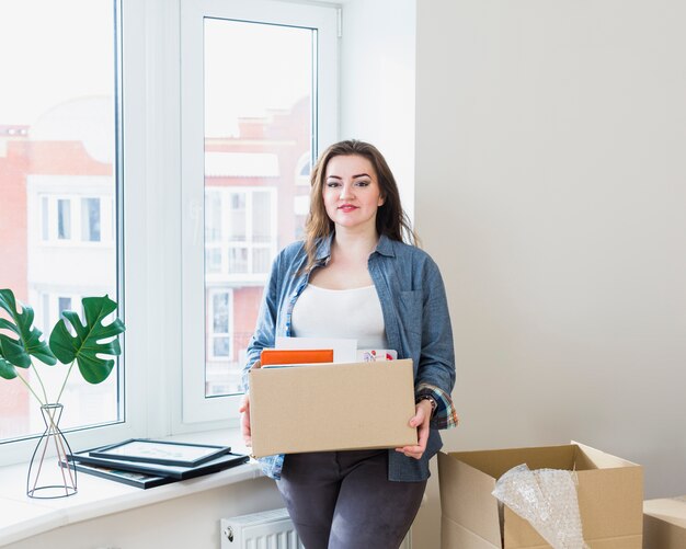 Retrato de una joven y bella mujer desempacando cajas de cartón en su nuevo hogar