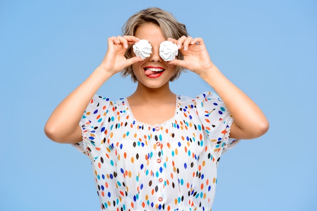 Retrato de joven bella mujer con dulces sobre pared azul