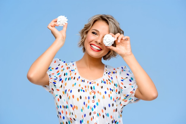 Retrato de joven bella mujer con dulces sobre pared azul